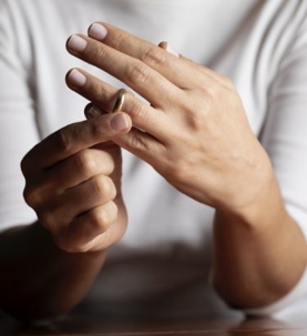 Person removing wedding ring from finger.