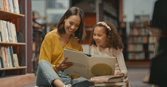 mother and daughter reading a book in a library