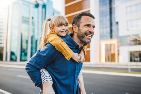 father giving daughter piggyback ride in city
